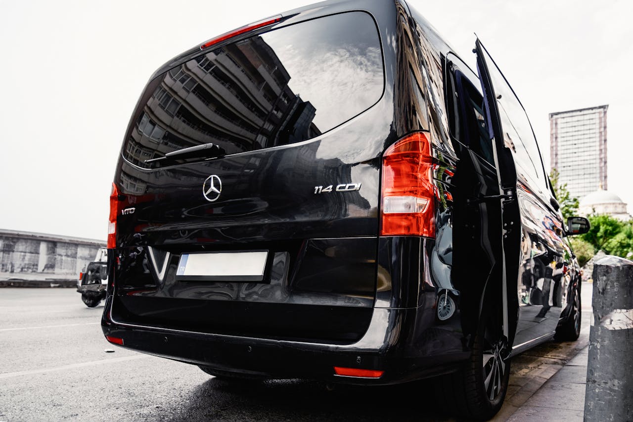 about-img Rear view of a black luxury van on a city street, showcasing urban lifestyle.
