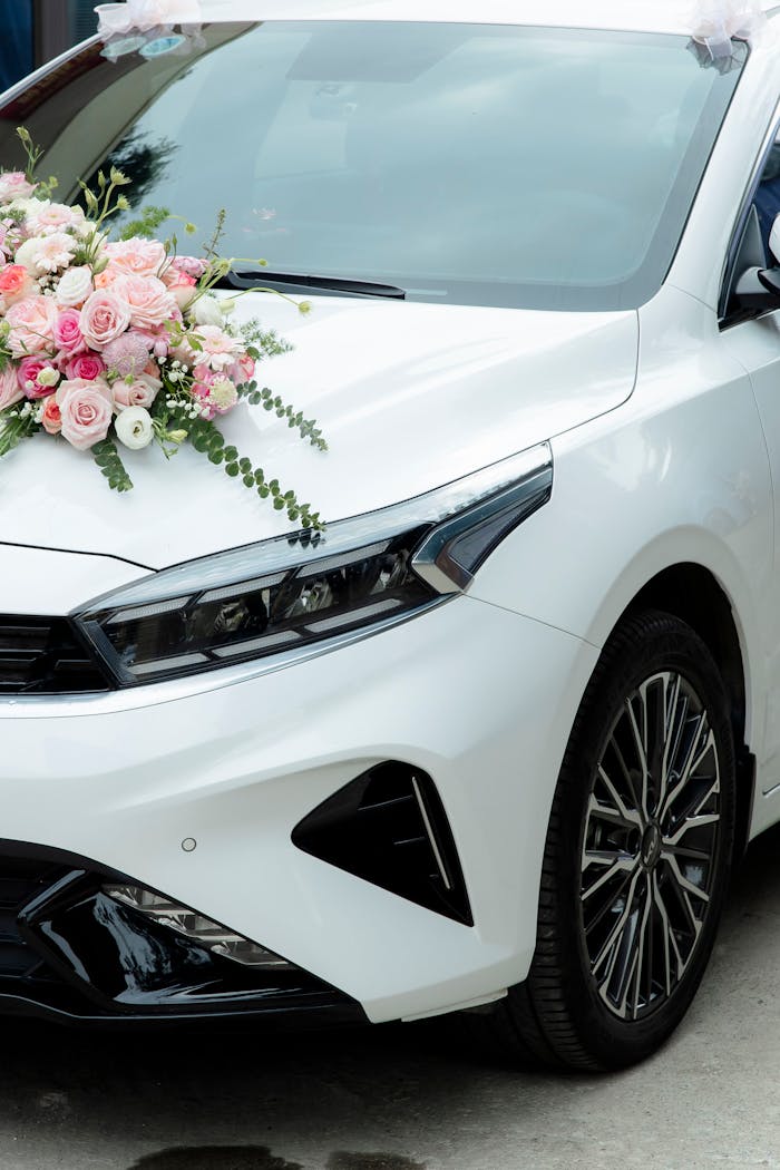 cta-02 Close-up of a white car adorned with pink and white floral arrangement for a wedding ceremony.