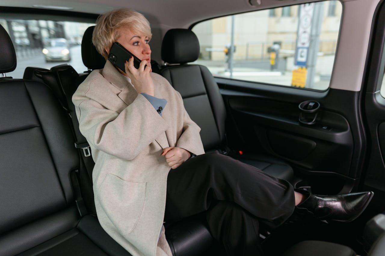gallery-img-06 Woman in a car making a phone call, wearing a coat and resting comfortably.
