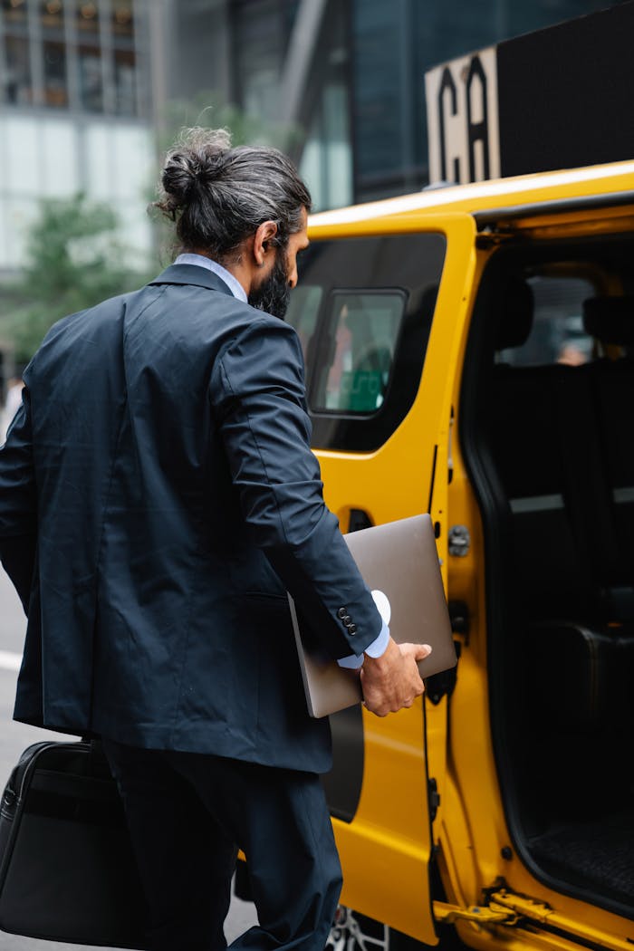 why-choose-us-img Professional man in formal wear entering a yellow taxi on a city street.